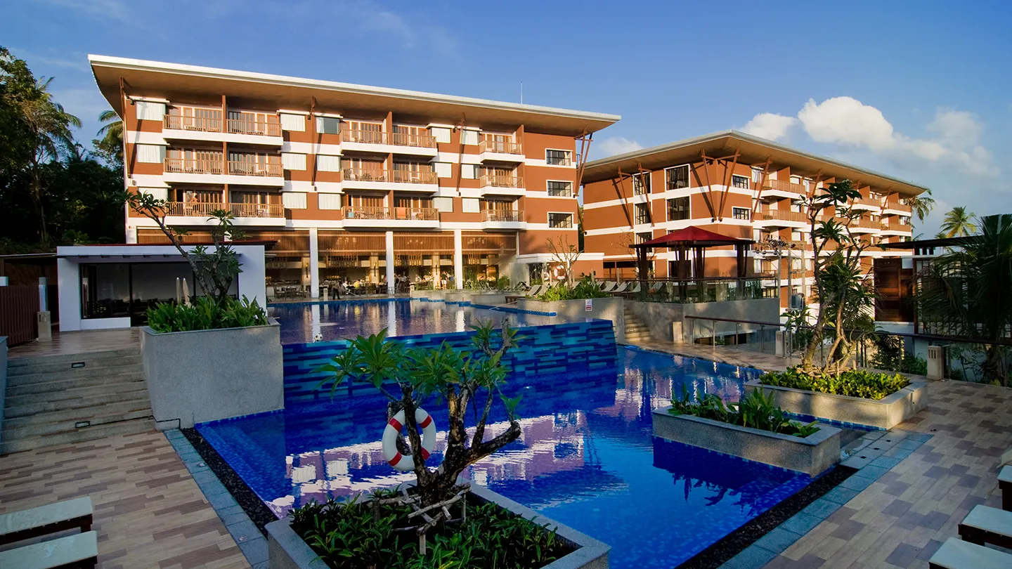 Large tropical pool area at Peach Blossom Resort Phuket with modern hotel building